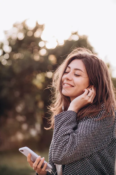 Gülümseyen Güzel Bir Genç Kadın Sokakta Kulaklıkla Telefondan Müzik Dinliyor — Stok fotoğraf