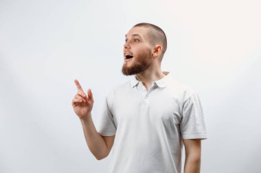 Beyaz tişörtlü yakışıklı bir gencin portresi beyaz arka planda bir parmağı olduğunu gösteriyor. İzole. duygular