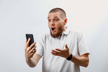 Beyaz tişörtlü yakışıklı bir adamın portresi video görüşmesinde akıllı telefon kullanarak konuşuyor. İzole. duygular
