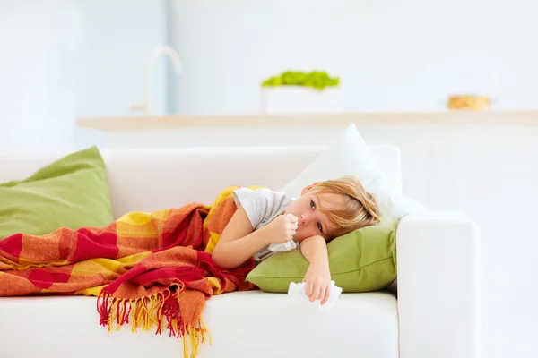 Nemocné dítě s výtok z nosu a horečka tepla leží na gauči doma — Stock fotografie