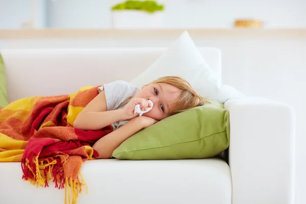 Enfant malade avec écoulement nasal et fièvre chaleur couché sur le canapé à la maison — Photo