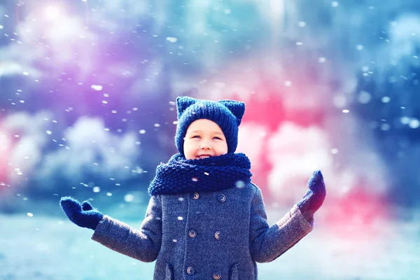 Cute happy kid under the snow in winter park — Stock Photo, Image