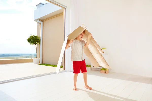 Menino feliz bonito brincando com caixa de papelão em casa — Fotografia de Stock