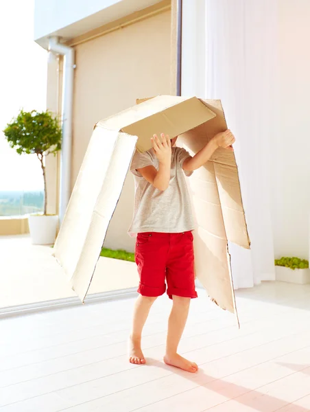 Милий щасливий хлопчик грає з картонною коробкою вдома — стокове фото