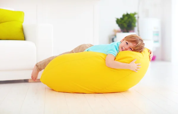 Niño feliz divirtiéndose en bolsa de frijol amarillo en casa —  Fotos de Stock