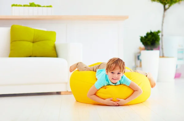 Bambino eccitato divertirsi sulla borsa di fagioli gialli a casa — Foto Stock