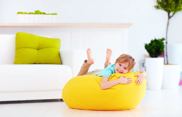 Excited kid having fun on yellow bean bag at home — Stock Photo, Image