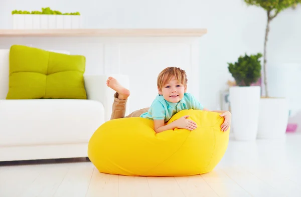 Szczęśliwe dziecko zabawy na fasoli żółty worek w domu — Zdjęcie stockowe