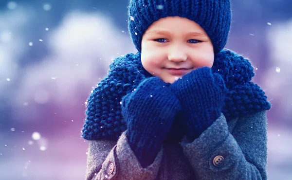 Garoto bonito no desgaste de malha e casaco feltrado sob neve de inverno — Fotografia de Stock