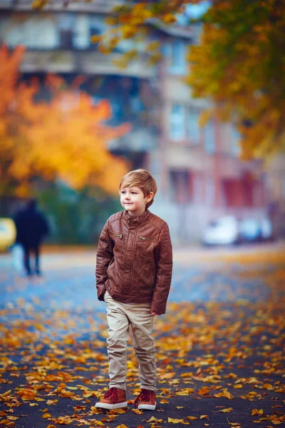 Cute boy walking through the autumn city street — Stock Photo, Image