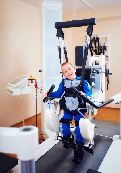 Молодий хлопчик проходить терапію роботизованої ходи в реабілітаційному центрі — стокове фото