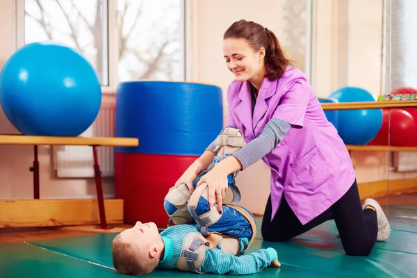 Carino bambino con disabilità ha terapia muscolo-scheletrica facendo esercizi nelle cinture di fissaggio del corpo — Foto Stock