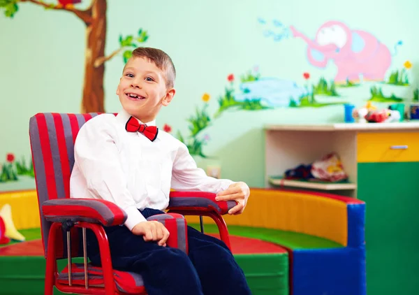 Χαριτωμένο ευτυχισμένο παιδί σε αναπηρικό καρότσι, φορώντας τα καλά κουρέλια στο κέντρο για παιδιά με ειδικές ανάγκες — Φωτογραφία Αρχείου
