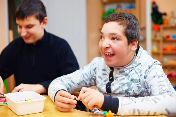 Niños felices con discapacidad desarrollan sus habilidades motoras finas en el centro de rehabilitación para niños con necesidades especiales — Foto de Stock