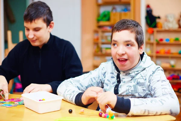 Niños felices con discapacidad desarrollan sus habilidades motoras finas en el centro de rehabilitación para niños con necesidades especiales — Foto de Stock