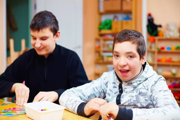 Crianças felizes com deficiência desenvolvem suas habilidades motoras finas no centro de reabilitação para crianças com necessidades especiais — Fotografia de Stock