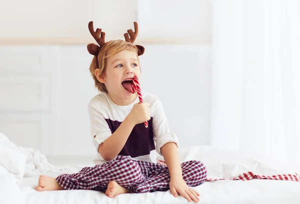 Garoto bonito lambendo doces de Natal na manhã de inverno — Fotografia de Stock