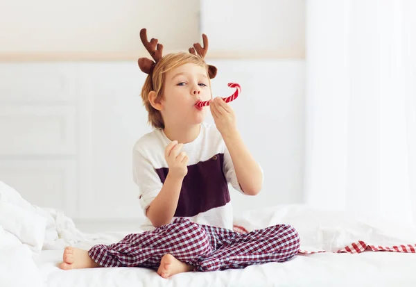 Милый ребенок лижет рождественские конфеты зимой утром — стоковое фото