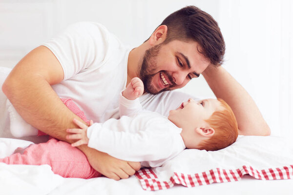 счастливый отец играет с восхитительным ребенком в спальне
