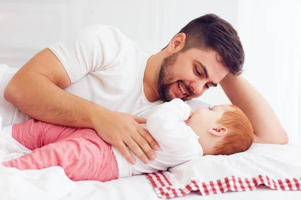 Счастливый отец играет с восхитительным ребенком в спальне — стоковое фото