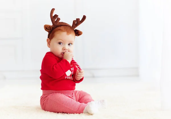 Mignonne rousse bébé manger des bonbons de Noël à la maison — Photo