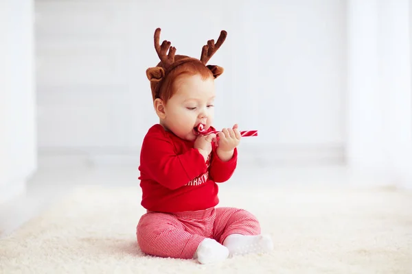Mignonne rousse bébé manger des bonbons de Noël à la maison — Photo