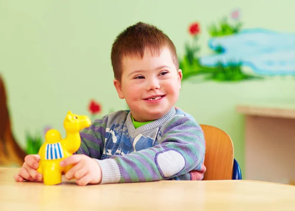 Мила дитина з синдромом Дауна грає в дитячому саду — стокове фото