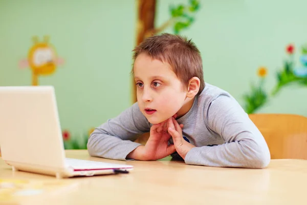 Niño con necesidades especiales viendo vídeo a través de la computadora portátil —  Fotos de Stock