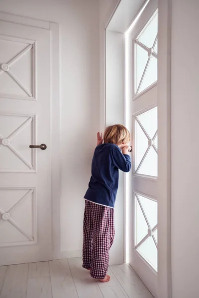 Nieuwsgierige jonge jongen kijkt in de kier van de deur — Stockfoto