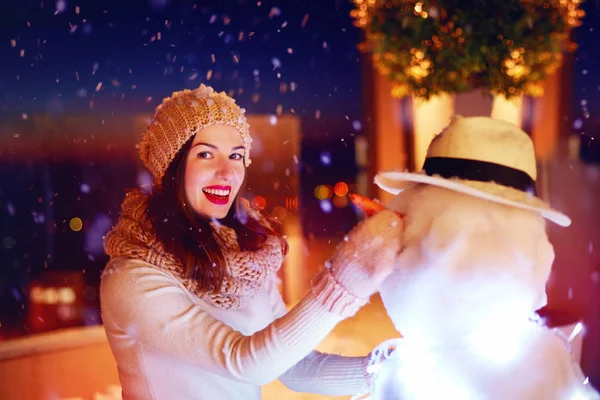 Hermosa mujer feliz haciendo muñeco de nieve bajo la nieve mágica invierno —  Fotos de Stock