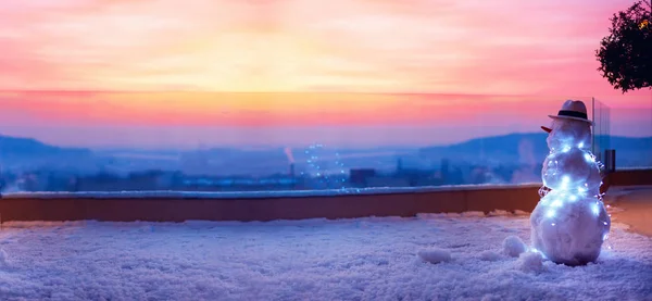 Söt snögubbe se solen går ner på takterrassen — Stockfoto