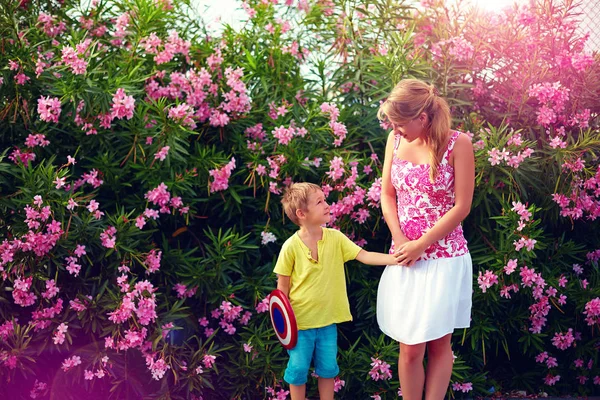 Young woman and kid talking in front of blooming garden — Stock Photo, Image