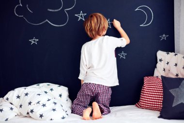 şirin çocuk pijama onun yatak odasında kara tahta duvar boyama