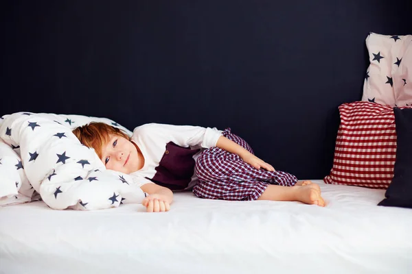 Garoto bonito vestindo pijama, menino relaxado deitado na cama — Fotografia de Stock