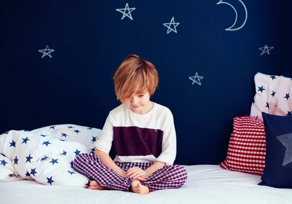 Bonito sorrindo garoto no pijama sentado na cama — Fotografia de Stock