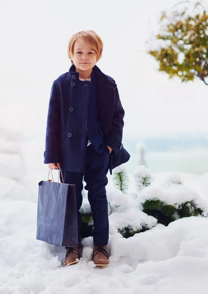 Módní, sedm let starý chlapec v kabátě, drží tašku venku — Stock fotografie
