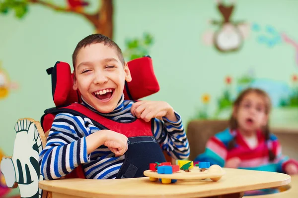 Веселый мальчик с ограниченными возможностями в реабилитационном центре для детей с особыми потребностями — стоковое фото