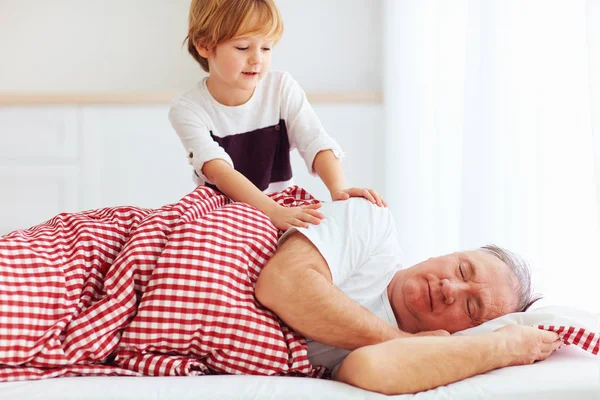 Cute grandson gently wakes hid grandpa up — Stock Photo, Image