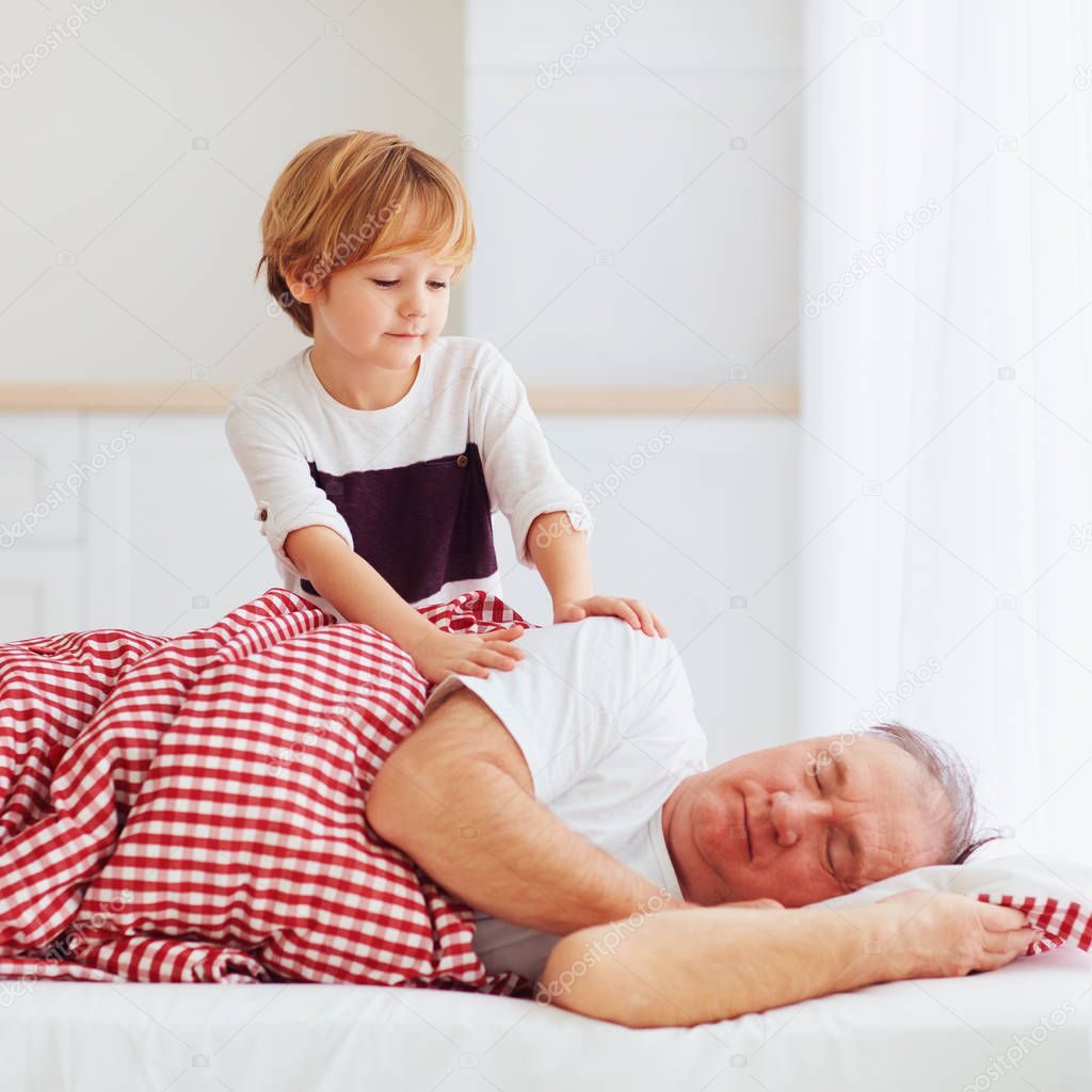 cute grandson gently wakes hid grandpa up