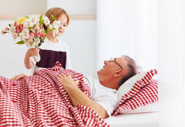 Young grandson with flower bouquet came to visit his sick grandpa in hospital ward — Stock Photo, Image