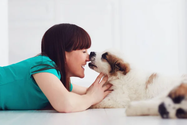 Momento engraçado de filhote de cachorro bonito lambendo rindo jovem mulher — Fotografia de Stock