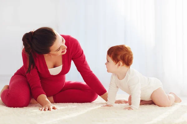 Madre embarazada feliz y bebé pequeño jugando en casa —  Fotos de Stock
