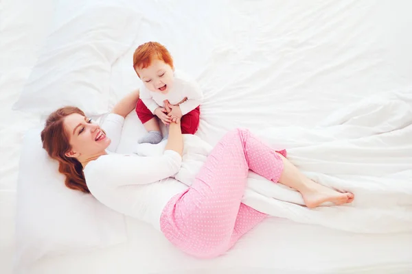 Счастливая мать играет со своим маленьким младенцем в постели — стоковое фото