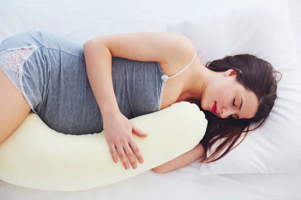 Bela mulher grávida dorme confortável com barriga almofada de apoio — Fotografia de Stock