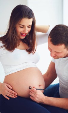 mutlu çift hamile karın üzerinde bir bebek adını yazma