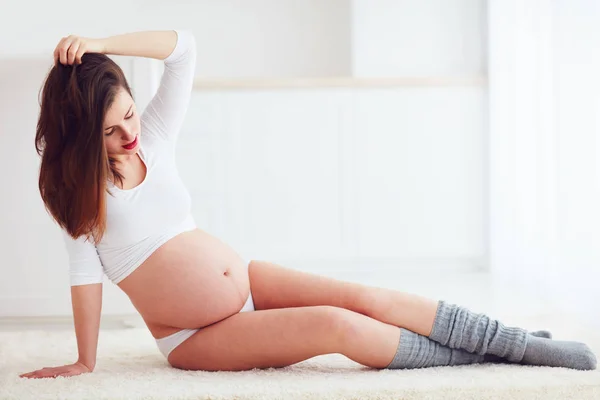 Krásná těhotná žena sedí na podlaze — Stock fotografie