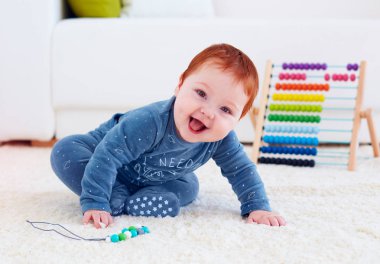 delighted happy infant baby playing on carpet at home clipart