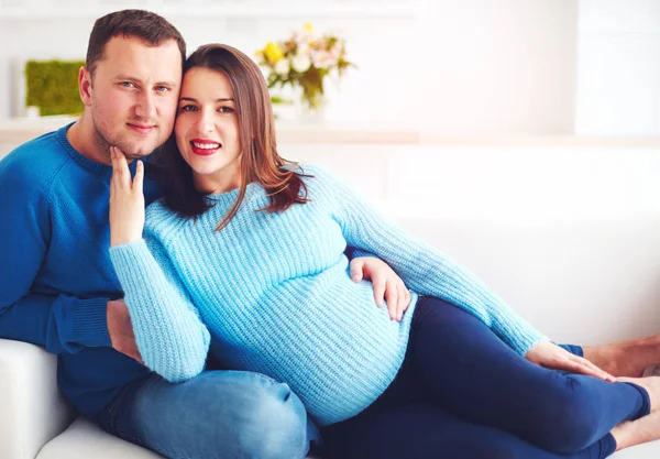 Feliz casal grávida relaxante no sofá em casa — Fotografia de Stock