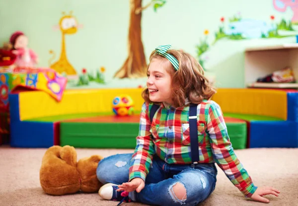 Menina feliz bonito jogando no jardim de infância para crianças com necessidades especiais — Fotografia de Stock