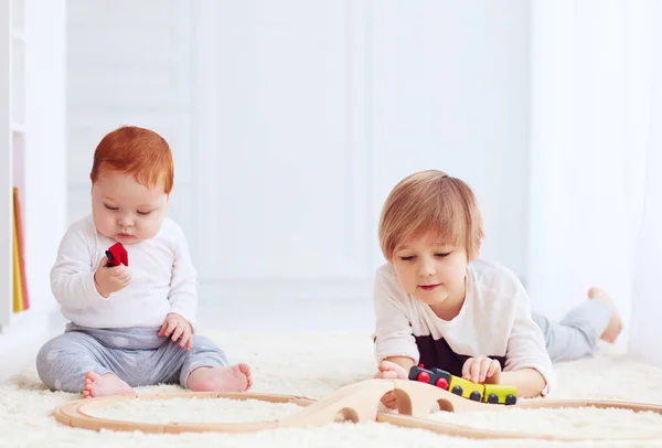 Bambini carini che giocano con la strada ferroviaria giocattolo a casa — Foto Stock